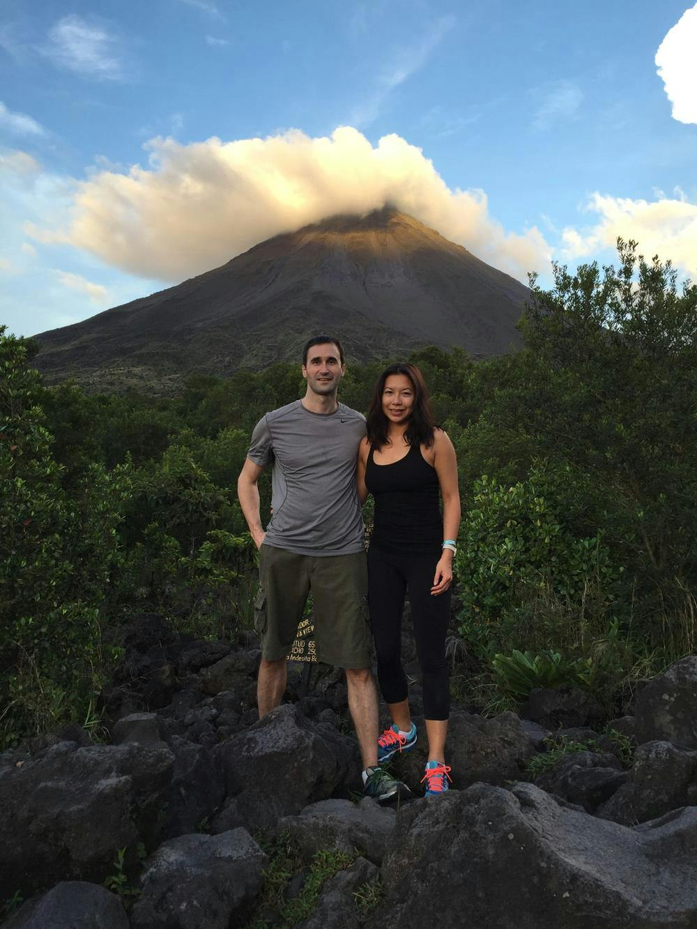 Robert and his partner standing in front of a volcano in athletic gear