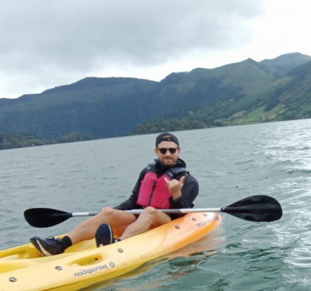 Marc Espada on a kayak in the water with mountains in the background