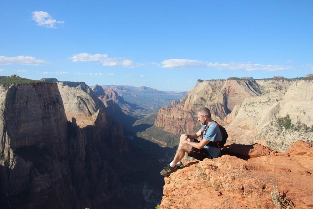Paul Hiom sitting on the edge of a cliff overlooking a canyon