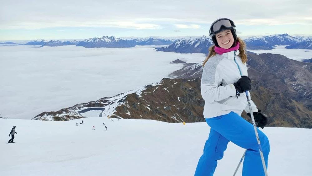 Kate smiling in skis in front of mountains