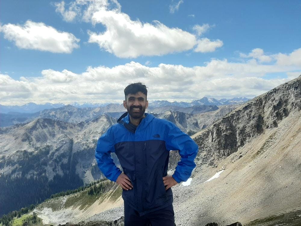 Jayant Nain standing on a mountain in front of other mountains