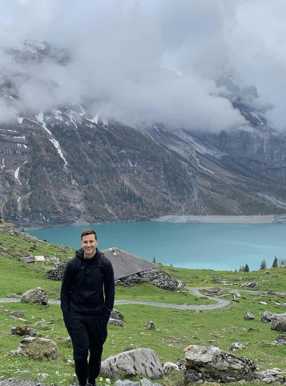 Kieran smiling in front a cloudy mountain and blue lake